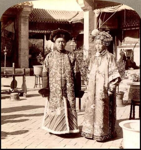 Bride and groom, wearing ornate Manchu wedding robes during Qing Dynasty. Notice the length, bagginess, and lack of a side split compared to a modern qipao.